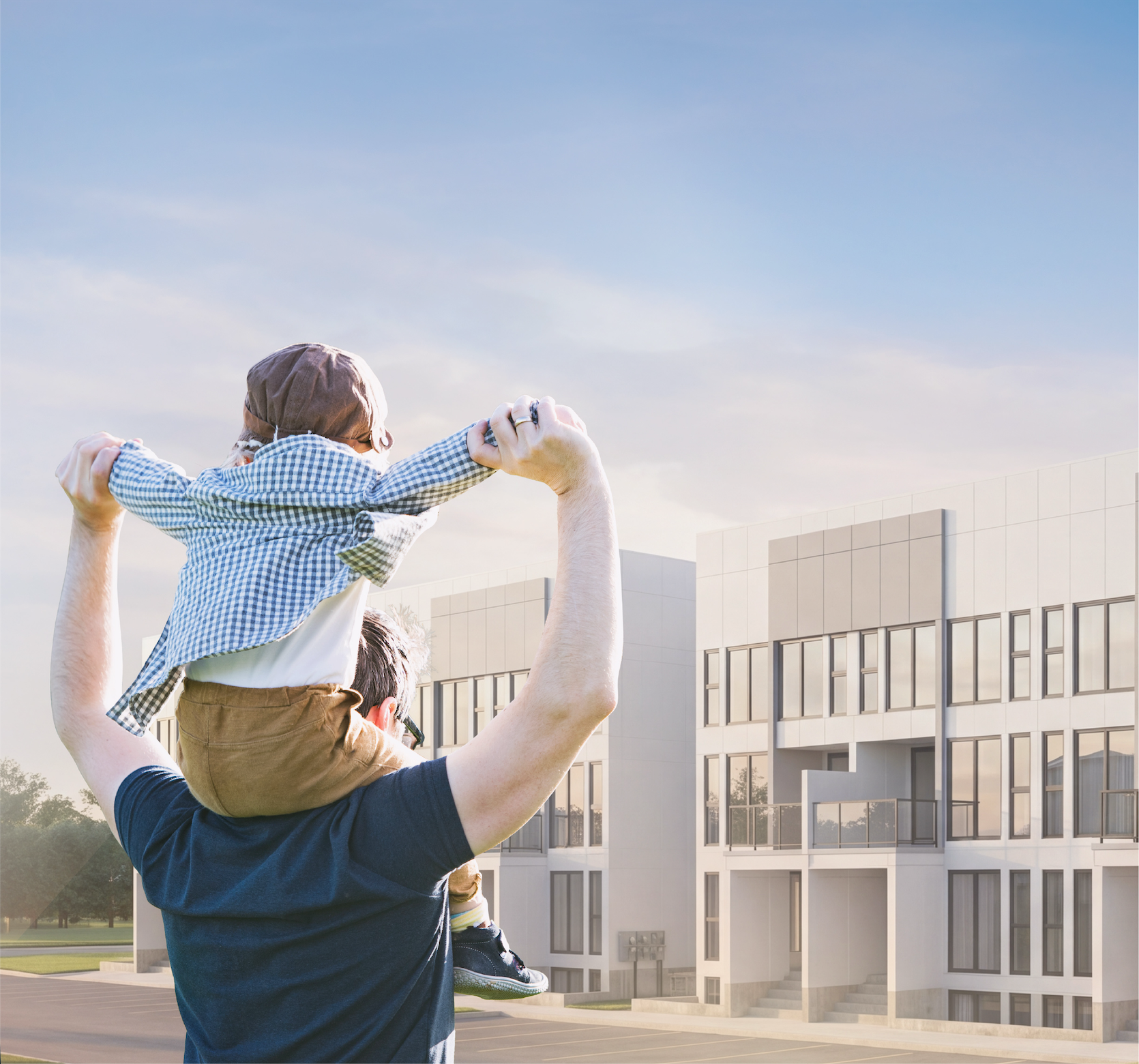 A parent lifting a child on their shoulders in front of new Drewlo townhomes